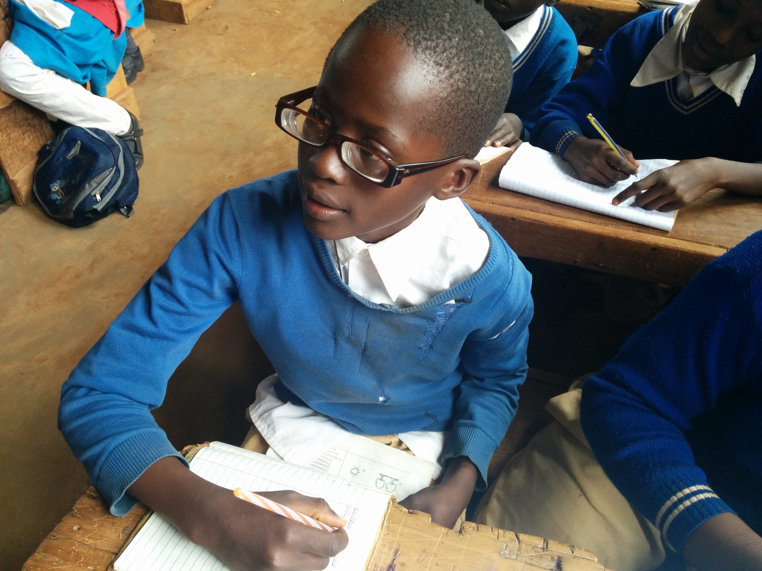 Young boy writing in school wearing eye-glasses