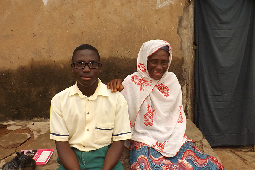 Woman sitting next to her grandson wearing eye-glasses.||