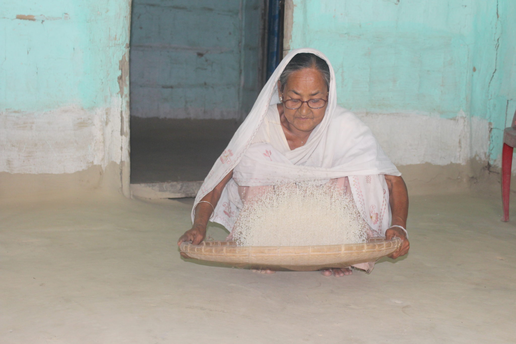 Picture of of Kuluki Saikia holding a basket of rice|Portrait of Kuluki Saikia
