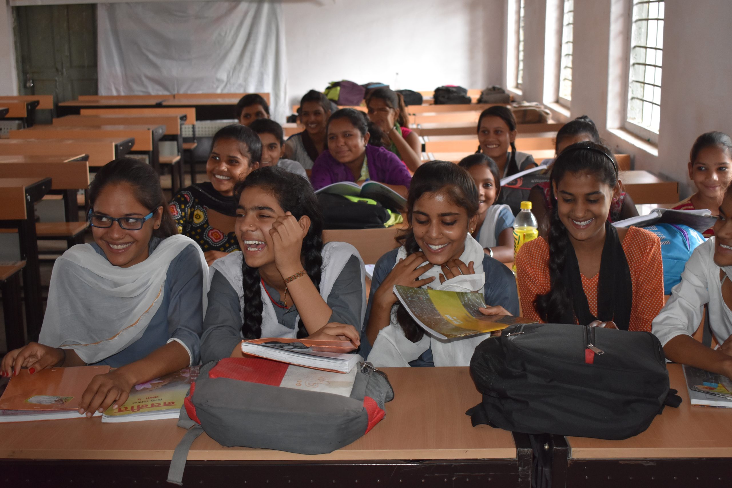 Young girls smiling together in a classroom|Portrait of a young girl named Tina wearing eye-glasses|Portrait of a young girl named Tina wearing eye-glasses
