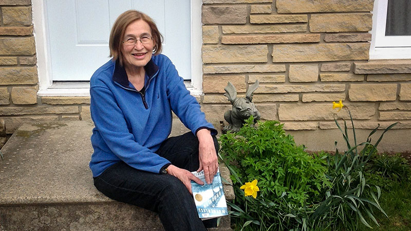 Woman sits on the front steps of her home