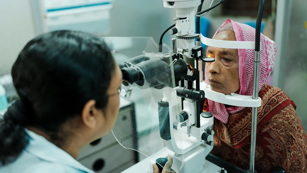 A health worker checks a woman's eyes through a slit lamp at a hospital in Bangladesh.|||||||||