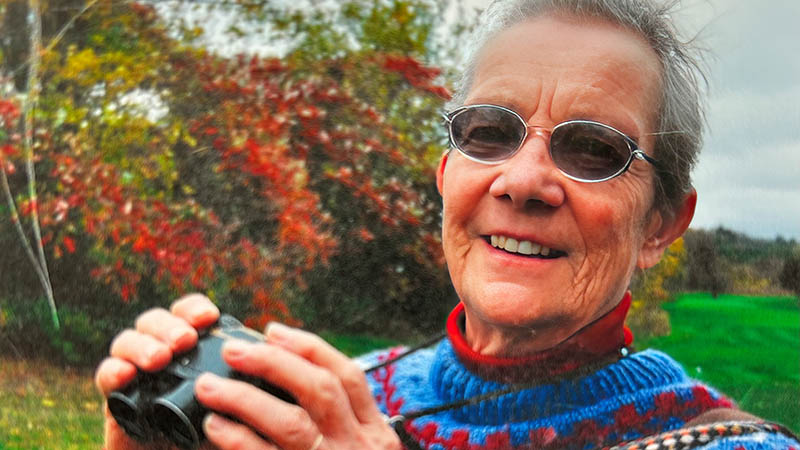 Woman wearing sunglasses holds up binoculars