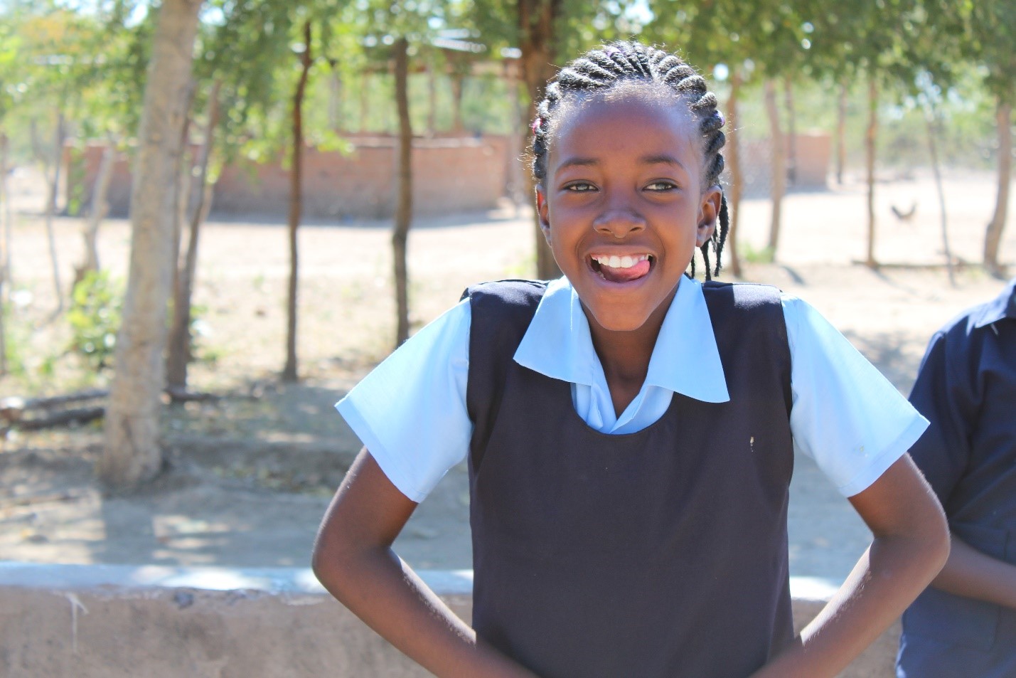 Portrait of young girl at Blessings school|Two girls and a young a water well at Blessing Schoo. young boy is drinking water.|Blessings School toilets