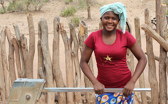 Ethiopia COVID-19|Men and woman standing in front of boxes and Operation Eyesight hand washing bins.|Men building a borehole in Zambia|Woman carrying child on her back washes her hands at water station in Zambia.|Group of men and boys circle around construction worker creating a borehole