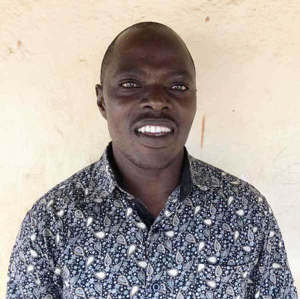 Portrait of Kizito|Kizito standing in front of a wall