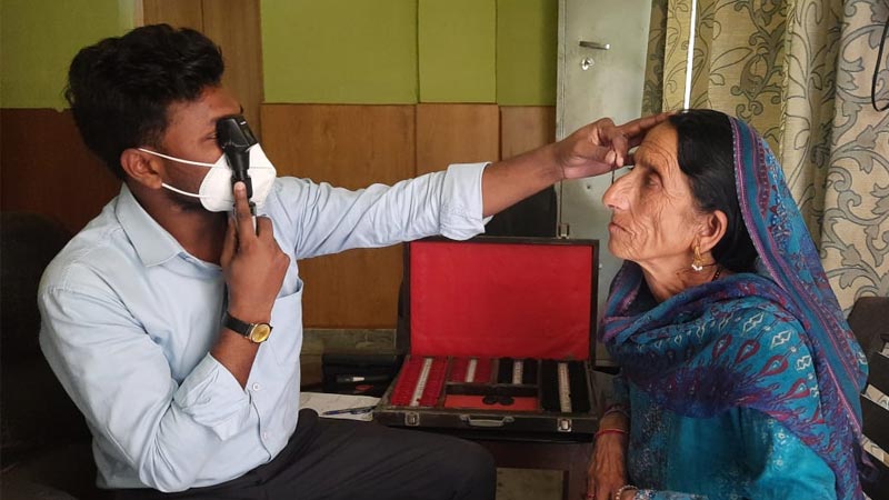A senior woman gets her eyes checked|A bus with the text "mobile optometry clinic" written on it|A senior woman gets her eyes checked with a slit lamp