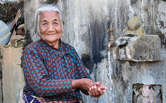 Senior woman washing hands from water faucet