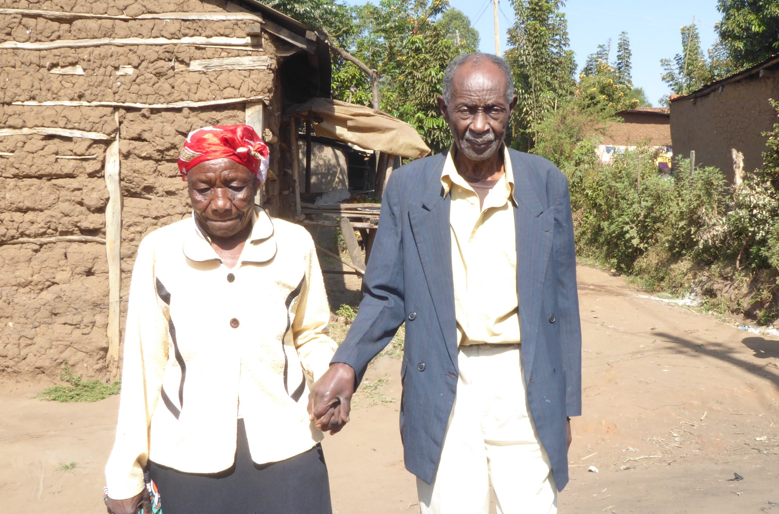 Kenyan couple holds hands as they walk to the car that will take them for sight-saving surgery|KEnyan man receoves sight-saving cataract surgery through Operation Eyesight|Philomena is a Kenyan woman who received sight-restoring cataract surgery through Operation Eyesight.