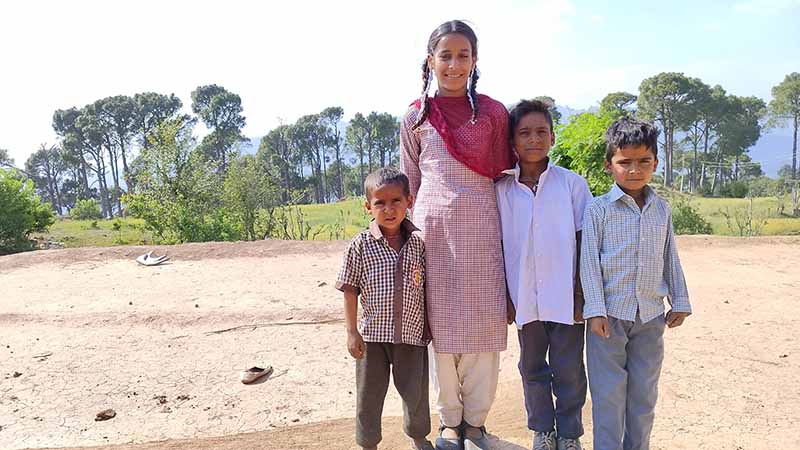 A young girls stands with three younger brothers.|A girl stands with her three younger brothers at her side