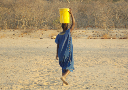 Zambian girl carrying a bucket of water on her head.|Now more girls can safely bring water to their families